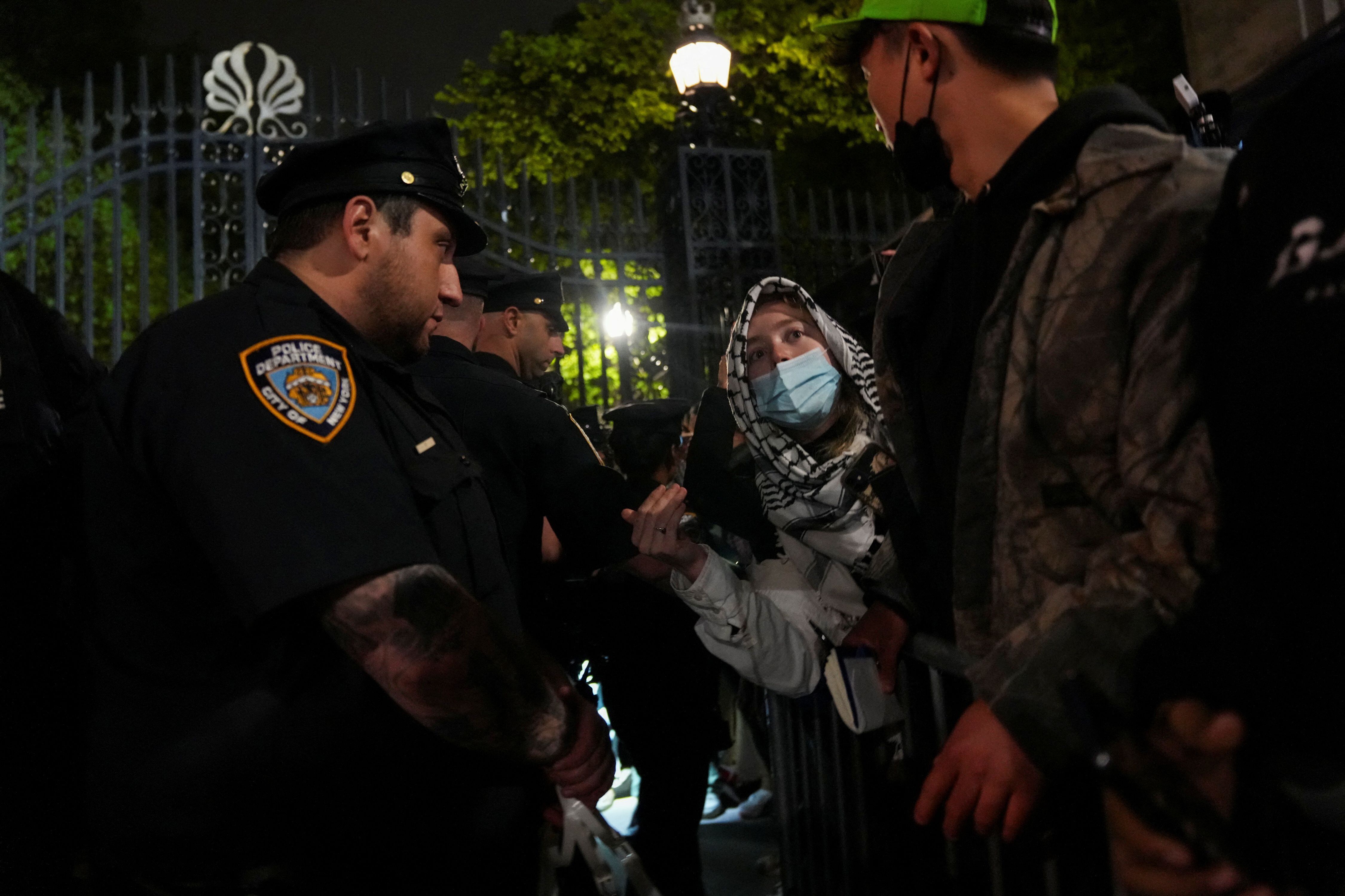 Una persona que lleva la keffiyeh palestina habla con agentes de policía mientras la policía mantiene un cordón alrededor de la Universidad de Columbia, donde los estudiantes se atrincheraron mientras continúan protestando en apoyo de los palestinos. REUTERS/David Dee Delgado