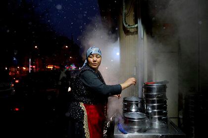 Una mujer de la minoría étnica musulmana uigur asiste a su puesto de comida en la ciudad de Urumqi, Región Autónoma Uigur de Xinjiang, China.  (EFE / How Hwee Young / Archivo)