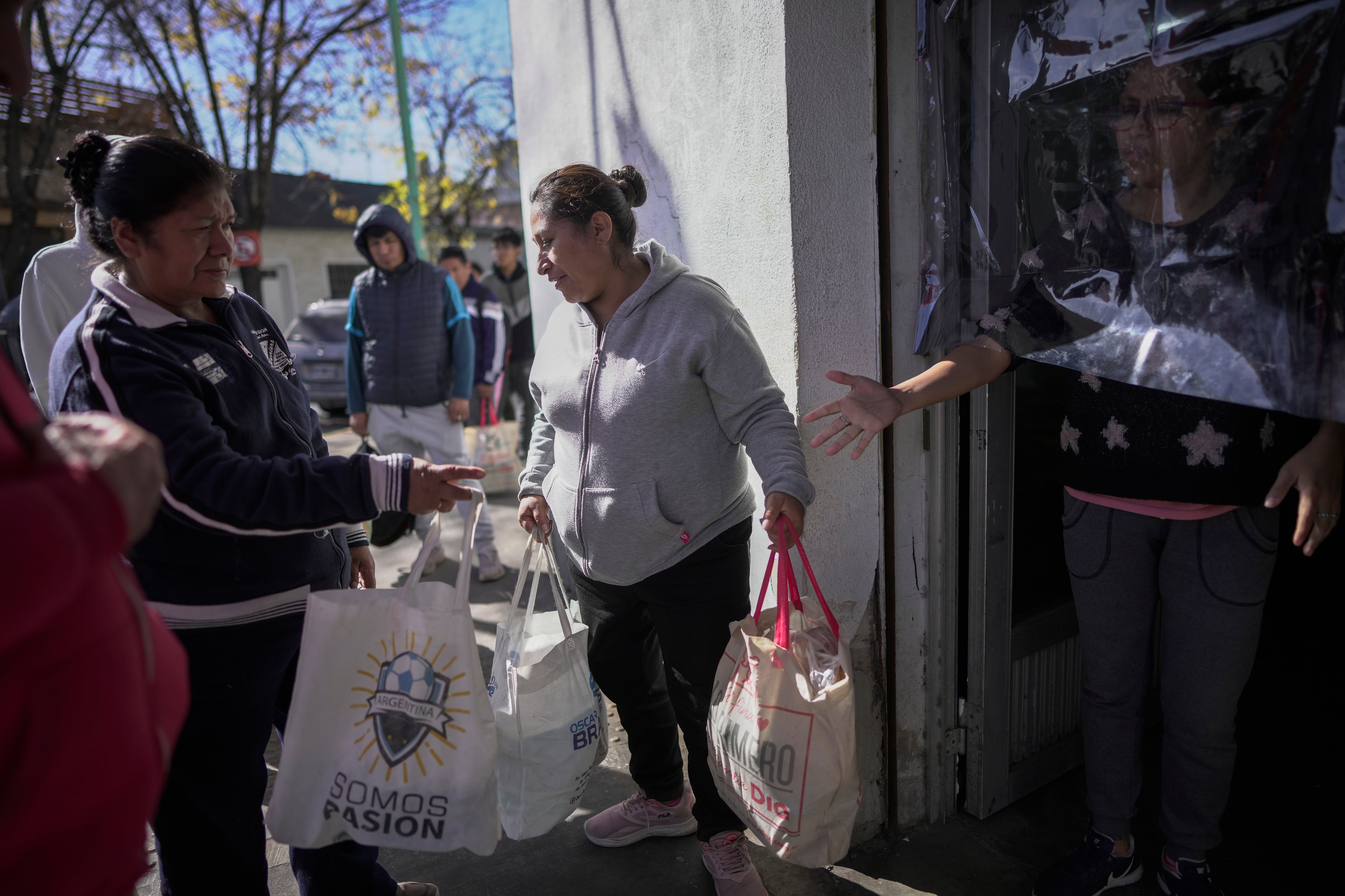 Las mujeres llevan bolsas de comida entregadas por un comedor social que sirve comidas calientes en el conurbano bonaerense. Muchas personas dependen de las entregas diarias de alimentos en medio de la inflación (Foto AP/Víctor R. Caivano)