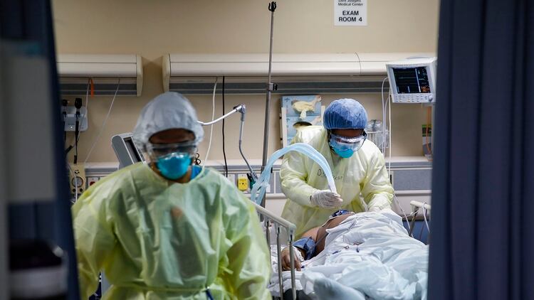 Una enfermera opera un ventilador en un paciente con COVID-19 que sufrió un paro cardíaco y fue reanimado por el personal (AP/John Minchillo)