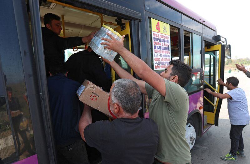 Voluntarios dan agua y comida a refugiados de la región de Nagorno Karabaj que llegan a la aldea fronteriza de Kornidzor, Armenia, el 29 de septiembre de 2023 (REUTERS/Irakli Gedenidze)
