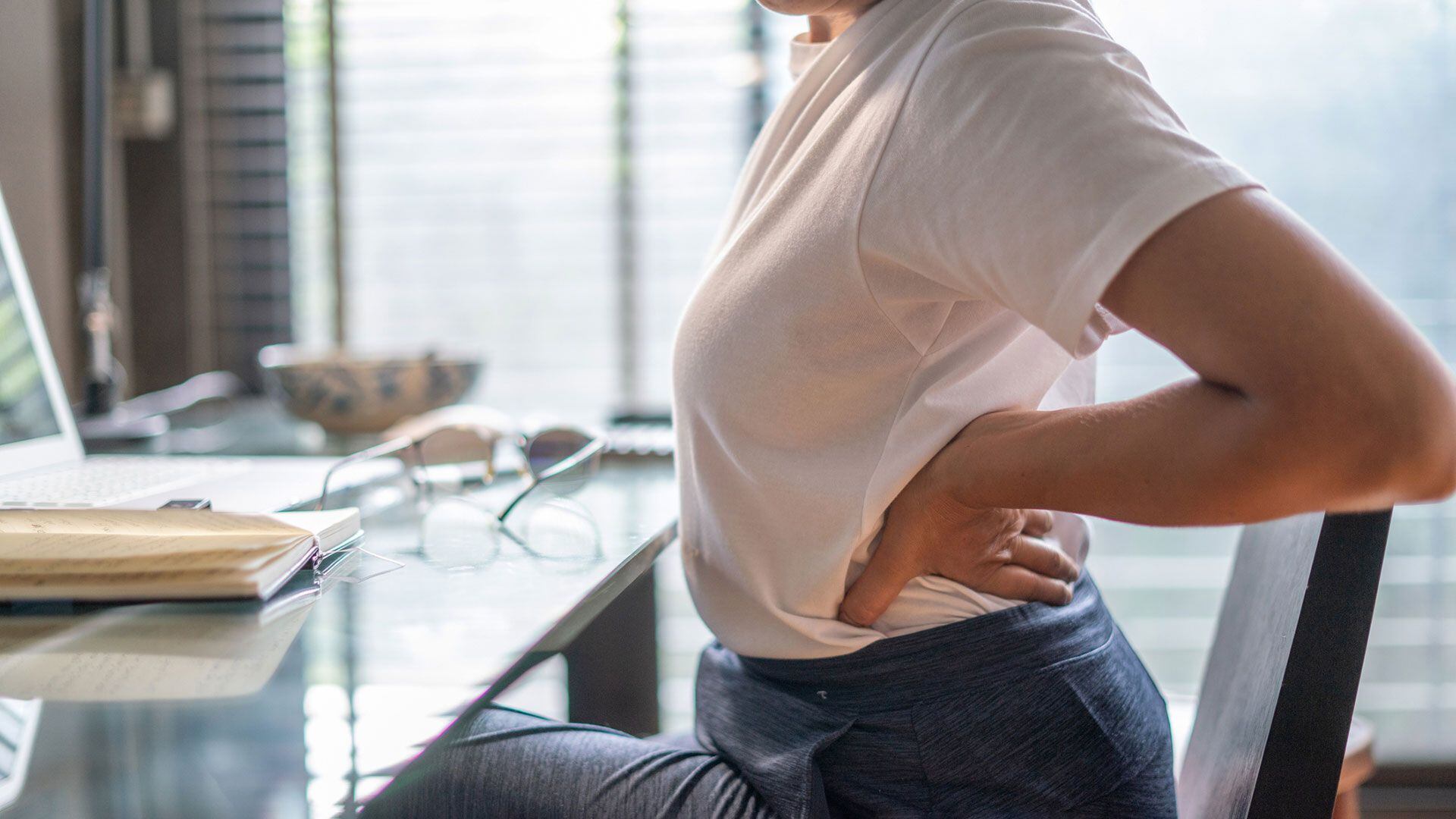 Una mujer sufre dolores en la espalda por el trabajo sedentario (Getty Images)