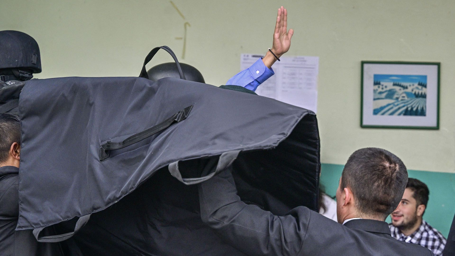 El candidato fue cubierto por un escudo protector cuando estaba en la mesa de votación. (MARTIN BERNETTI / AFP)