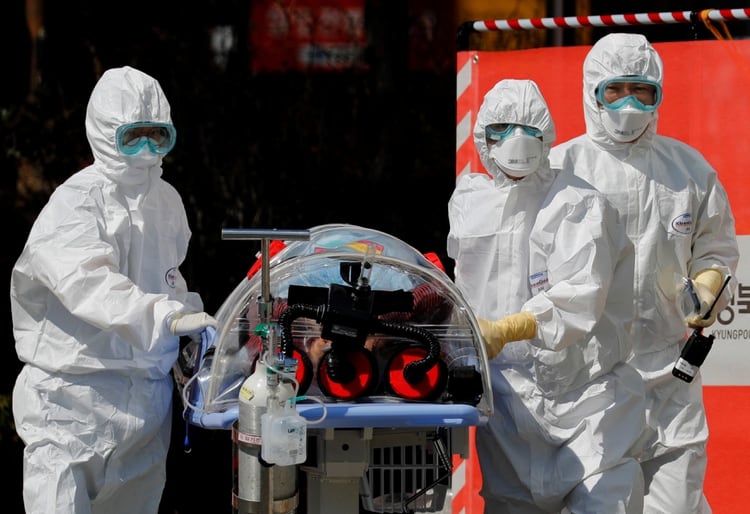 Trabajadores médicos llevan a un paciente en una camilla de aislamiento de presión negativa a una instalación del Hospital Universitario Nacional de Kyungpook en Daegu, Corea del Sur, el 6 de marzo de 2020 (REUTERS/Kim Kyung-Hoon)