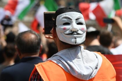 Un "chaleco naranja" con una máscara de Guy Fawkes durante la manifestación de este martes en Roma. (Vincenzo PINTO / AFP)
