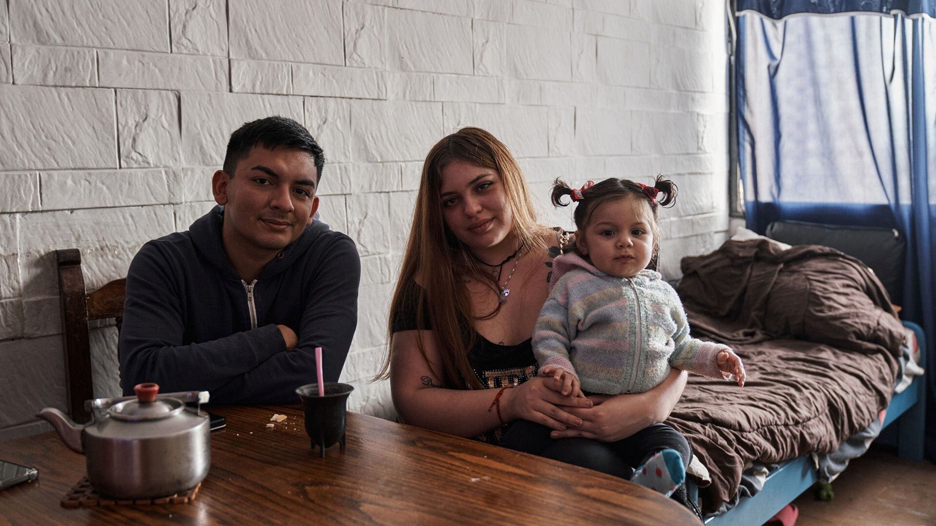 Oriana Gago y su pareja, Samir Santa Cruz, con su hija Chiara en el living del apartamento que alquilan en Lugano, Buenos Aires, Argentina.