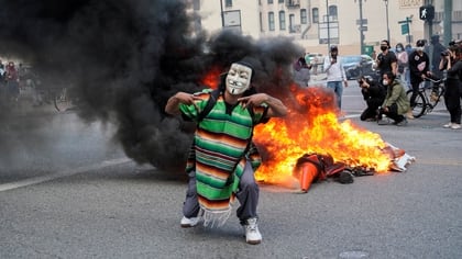 Un manifestante enmascarado se para frente al fuego durante una manifestación contra la muerte de George Floyd en Los Ángeles, California, el 30 de mayo de 2020. (REUTERS/Kyle Grillot)