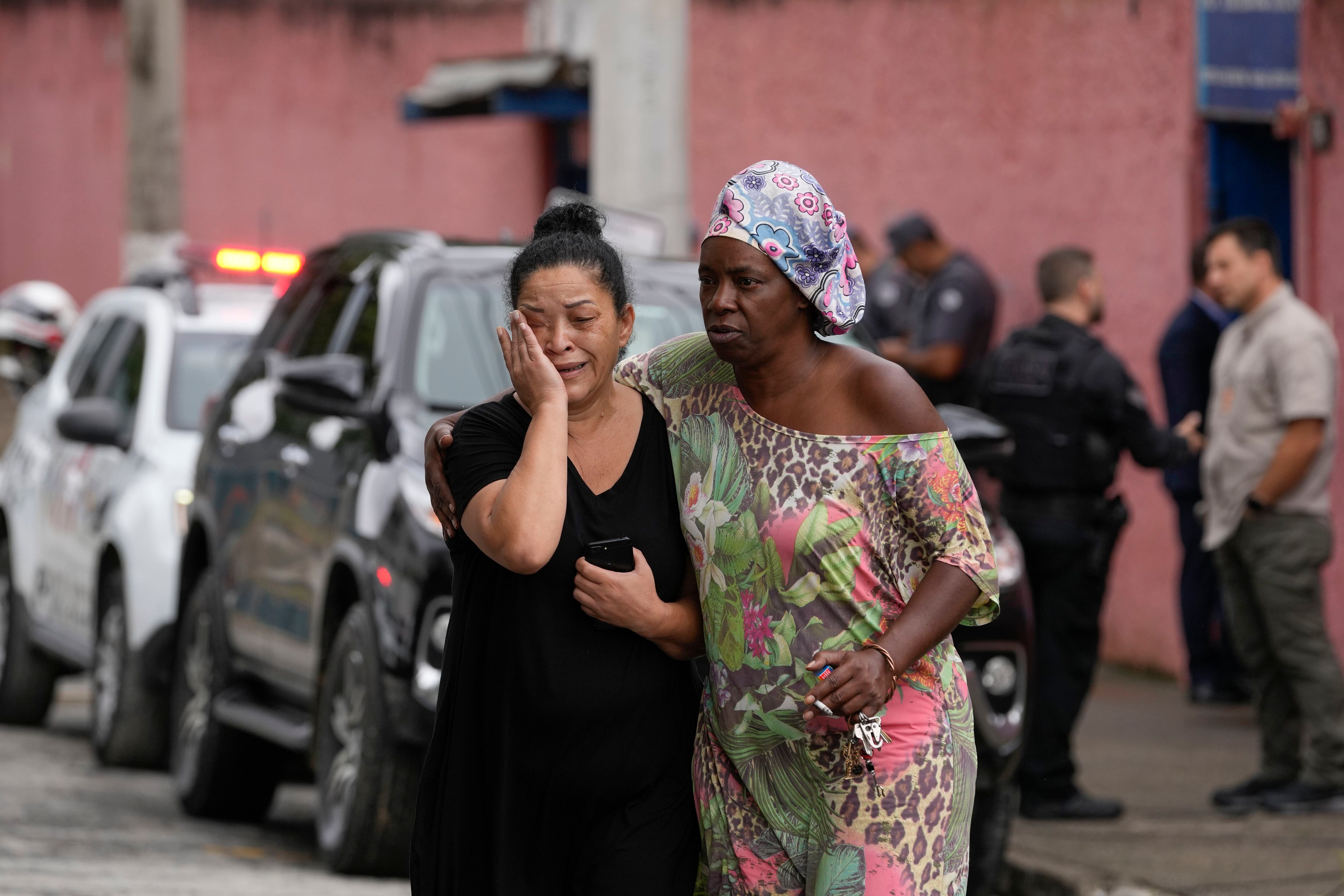 Silvia Palmieri (izquierda), quien es madre de una maestra que sobrevivió a un ataque a puñaladas en la escuela Thomazia Montorosale es consolada por una amiga el lunes 27 de marzo de 2023 en Sao Paulo, Brasil. Un estudiante de 13 años apuñaló fatalmente a una maestra de 71 años e hirió a tres maestras y dos compañeros el lunes en un ataque a puñaladas en la escuela pública, informaron funcionarios estatales. (AP Foto/Andre Penner)