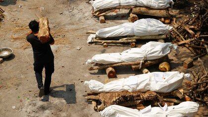 Un hombre traslada madera junto a las piras funerarias en un crematorio en Nueva Delhi. India, 26 de abril de 2021. REUTERS/Adnan Abidi