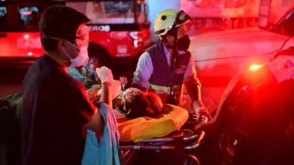 Los trabajadores de emergencia trasladan a una persona lesionada en una camilla en el lugar de un accidente de tren después de que una línea elevada del metro colapsara en la Ciudad de México (Foto de PEDRO PARDO / AFP)