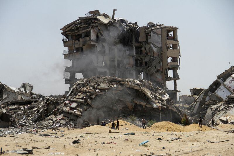 Palestinos caminan junto a los escombros de edificios residenciales destruidos por ataques israelíes, en medio del actual conflicto (REUTERS/Mahmoud Issa)
