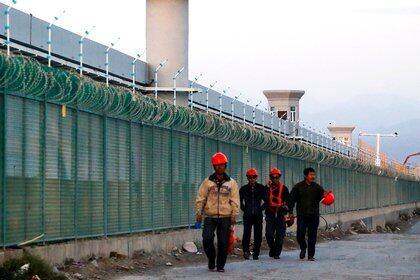 FILE PHOTO: Workers walk by the perimeter fence of what is officially known as a vocational skills education centre in Dabancheng in Xinjiang Uighur Autonomous Region, China September 4, 2018. This centre, situated between regional capital Urumqi and tourist spot Turpan, is among the largest known ones, and was still undergoing extensive construction and expansion at the time the photo was taken. Picture taken September 4, 2018. REUTERS/Thomas Peter/File Photo