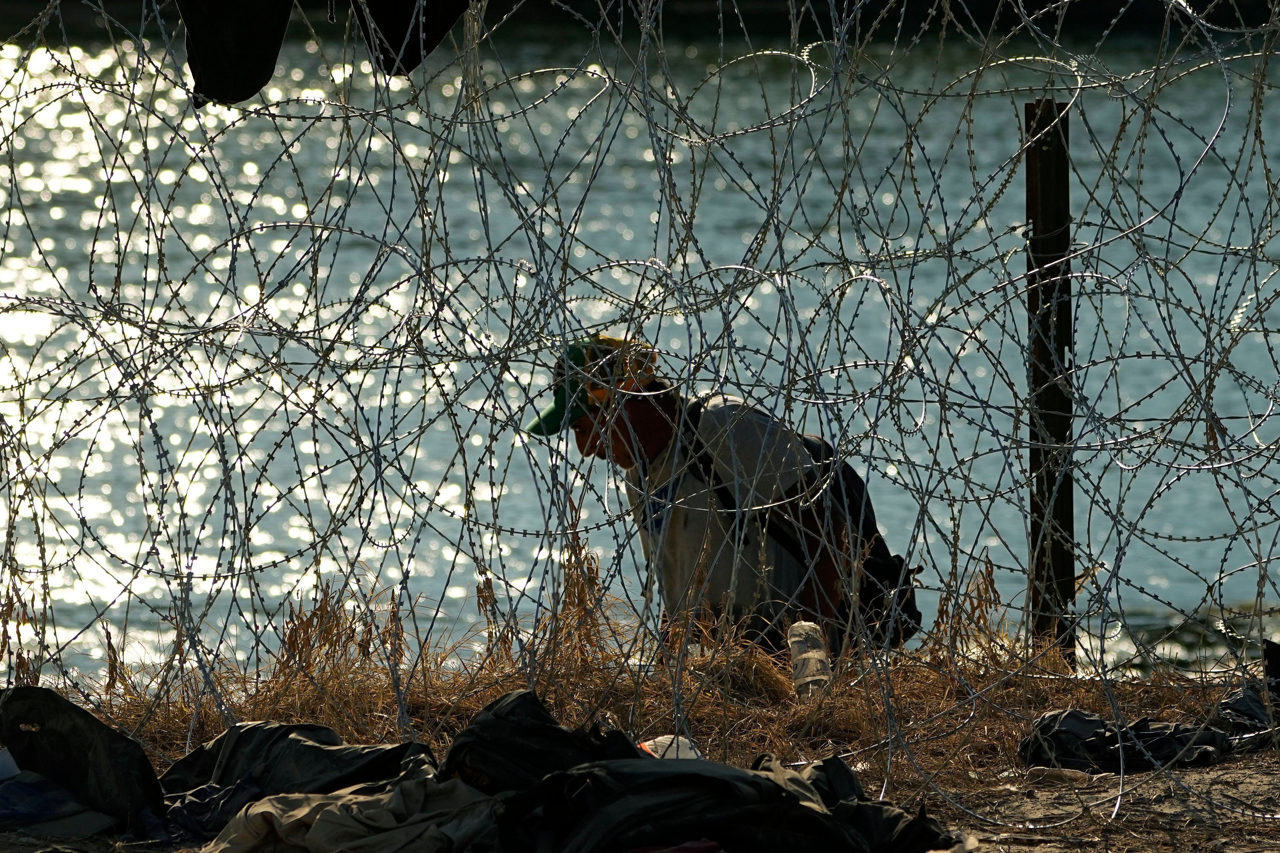Un migrante que cruzó el Río Bravo desde México a Estados Unidos busca una forma de cruzar los alambres en Eagle Pass, Texas. (Foto: AP Foto/Eric Gay)