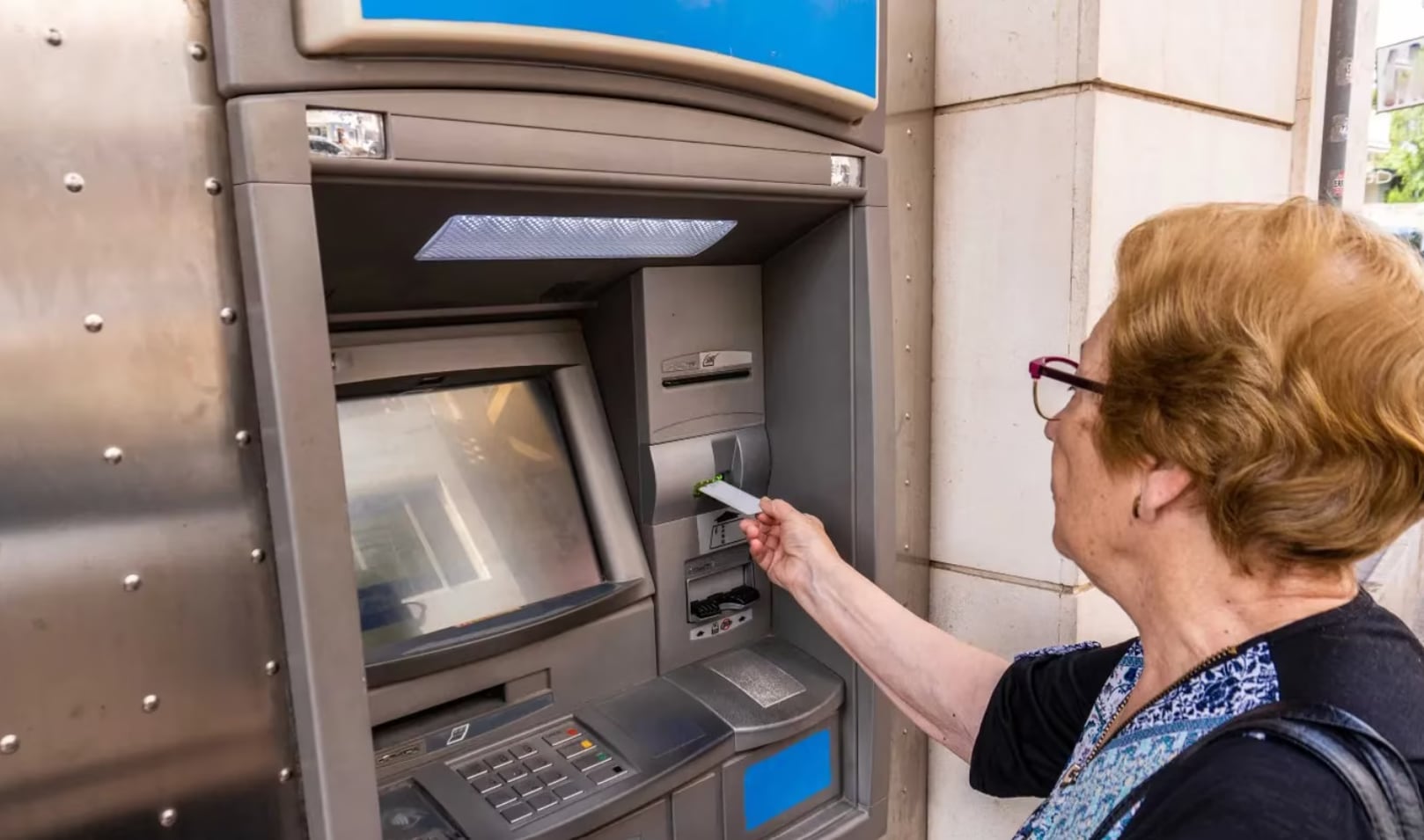 Una pensionista saca dinero en un cajero. (Adobe Stock)