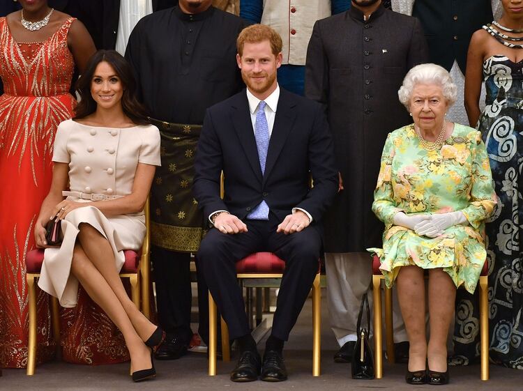 La reina Isabel II con su nieto Harry y Meghan Markle en un actor oficial en 2018. En el palacio de Buckingham se enteraron del anuncio cuando apareció en los canales de noticias (Shutterstock)