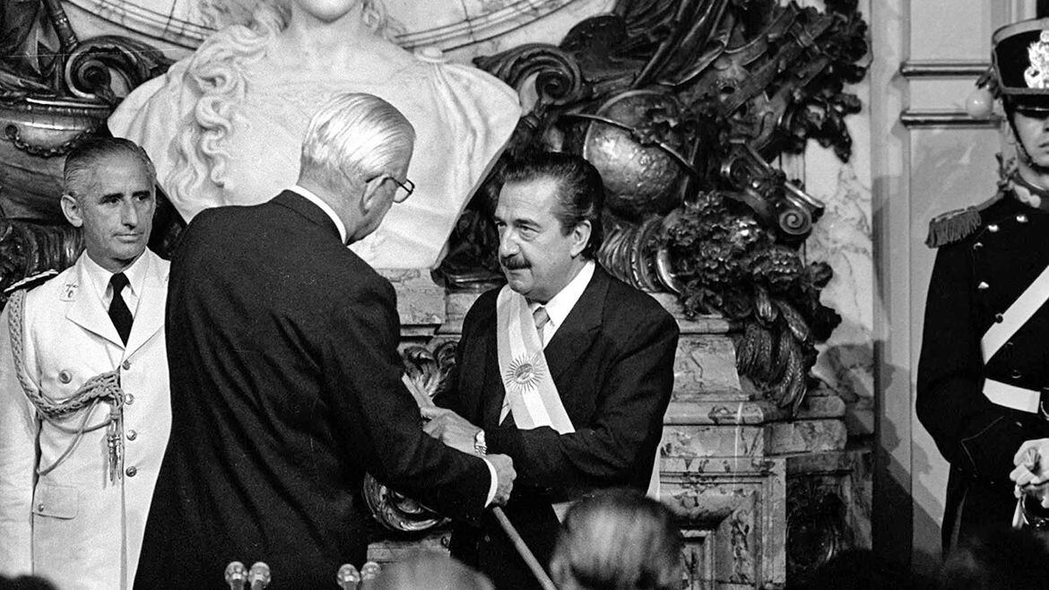 Raúl Alfonsín recibe la banda presidencial del último presidente de facto, Reynaldo Bignone, el 10 de diciembre de 1983 (AFP)