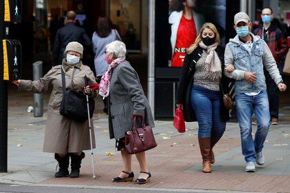 People wearing protective masks wait to cross the road, as the coronavirus disease (COVID-19) outbreak continues, in Manchester, Britain October 19, 2020. REUTERS/Phil Noble