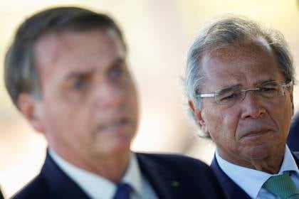El Ministro de Economía de Brasil, Paulo Guedes, escucha al Presidente Jair Bolsonaro mientras sale del Palacio Alvorada en Brasilia, el 27 de abril de 2020. (REUTERS/Ueslei Marcelino)