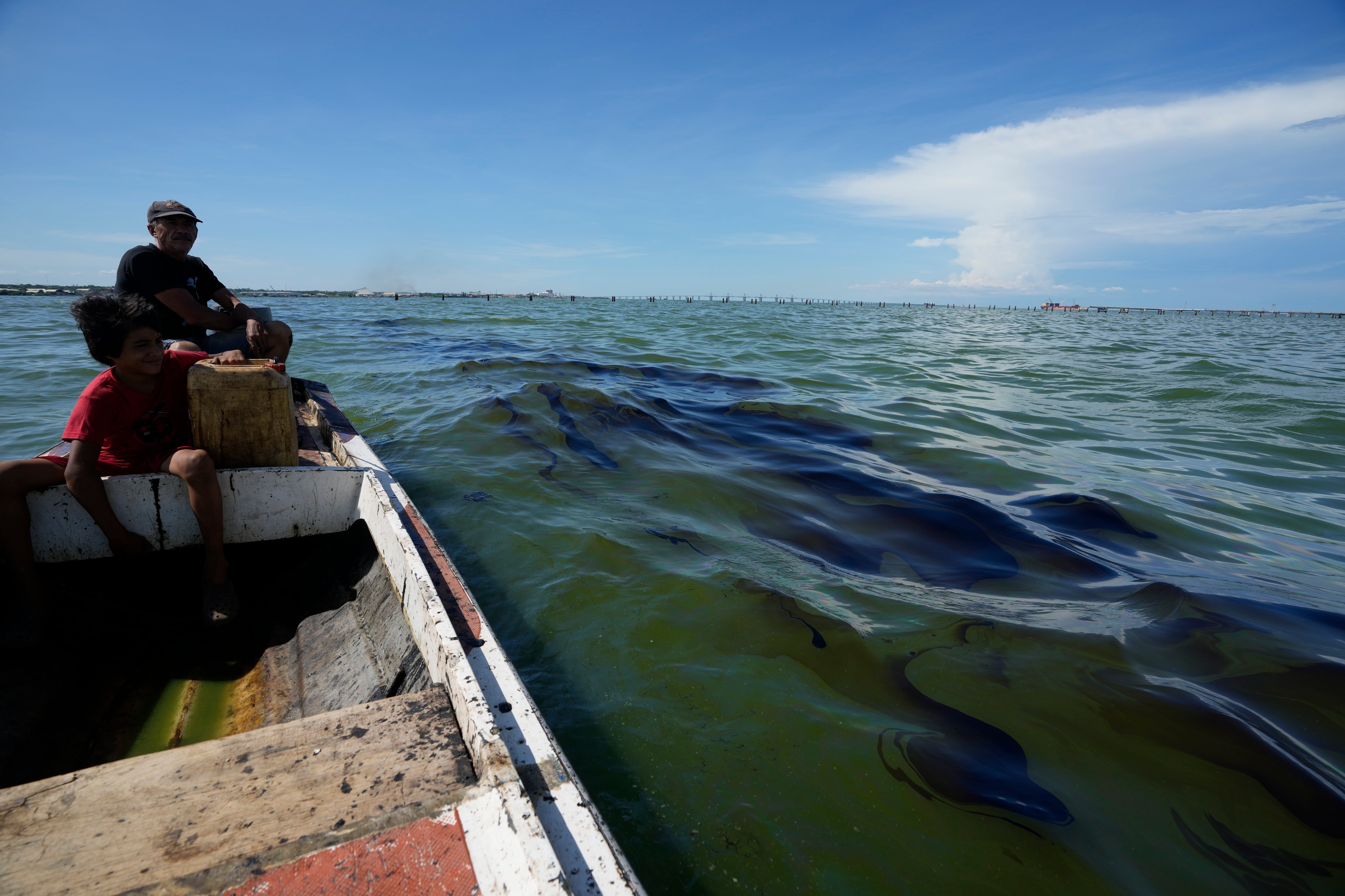 El pescador Óscar Luzardo navega en su bote y pasa al lado de una mancha de crudo   (AP Foto/Ariana Cubillos)