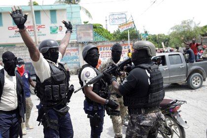 Protesters in police uniforms raise their arms as they face an on-duty Haitian National Police (PNH) officer holding a rifle during a protest organised by radical group "Fantom 509" in the streets of Port-au-Prince, Haiti September 14, 2020. REUTERS/Andres Martinez Casares