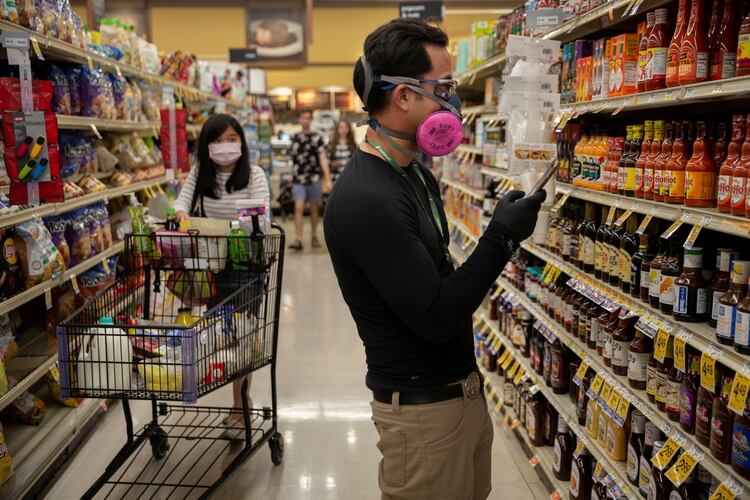 Eric Cohn, empleado de una empresa de delivery, busca un producto en el almacén de Safeway con una mascarilla puesta en Tucson, Arizona (Reuters/ Cheney Orr)