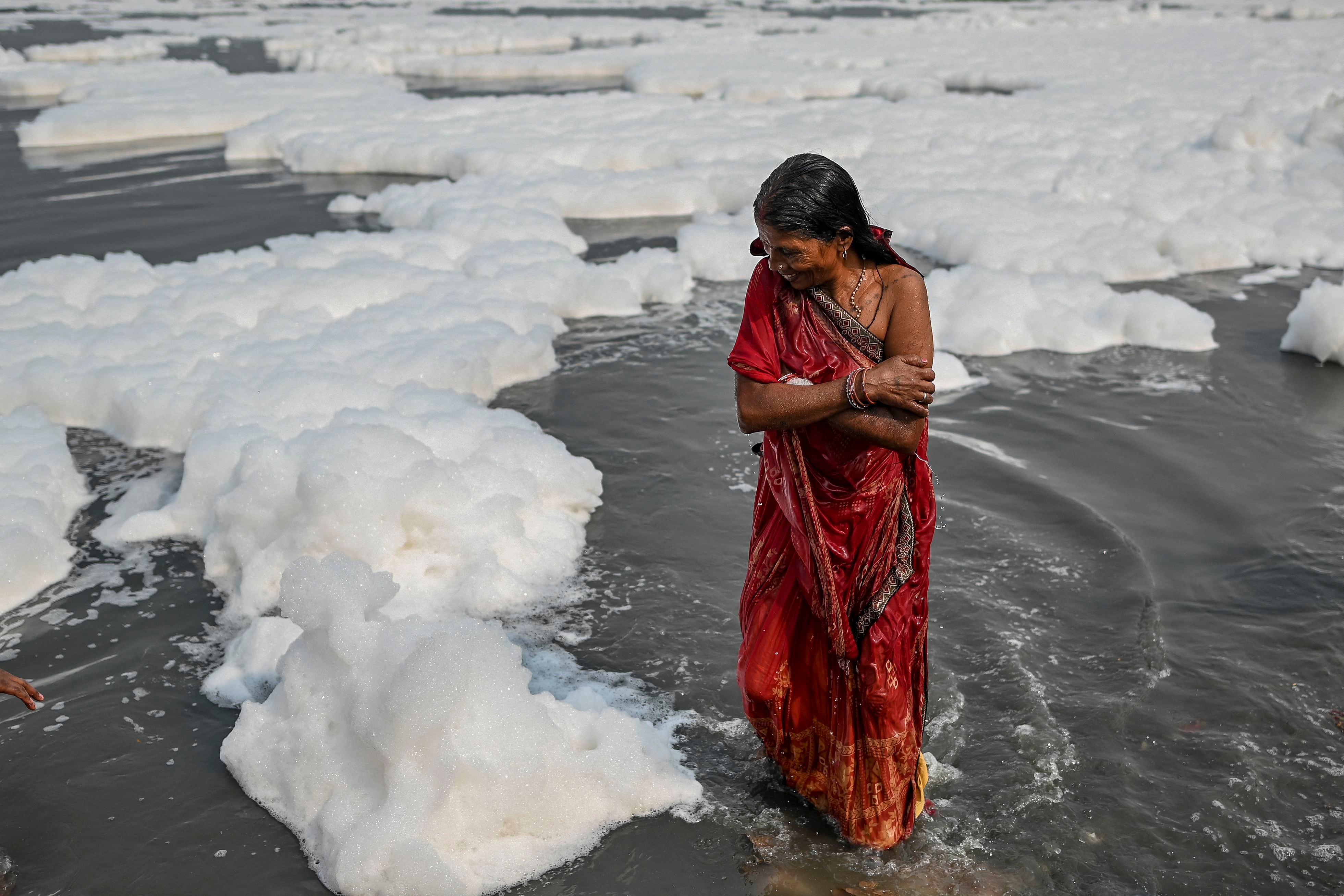 Una devota se da un chapuzón en las aguas del río Yamuna como parte de los rituales de festival hindú de Chhat Puja. (Sajjad HUSSAIN / AFP)