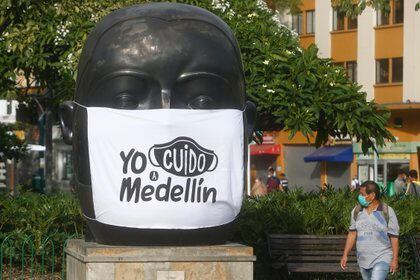 Un hombre con máscara fue registrado este martes mientras caminaba junto a una escultura de Fernando Botero con una máscara de campaña. "Yo cuido de medellín", con la que la Alcaldía busca concienciar sobre el autocuidado frente a la pandemia COVID-19 en Medellín (Colombia).  EFE / Luis Eduardo Noriega A