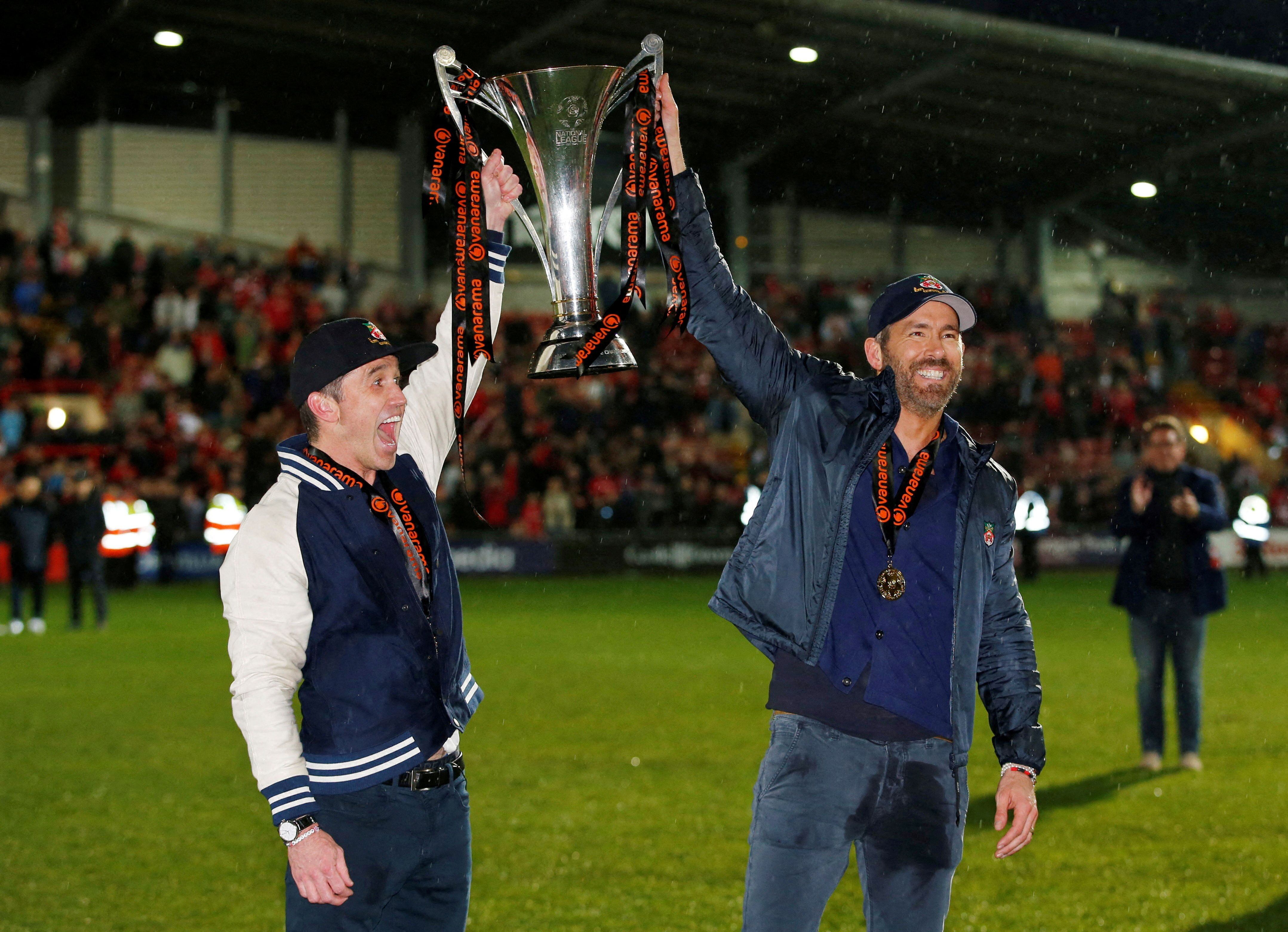 Los actores Ryan Reynolds y Rob McElhenney, dueños del Wrexham AFC, con el trofeo de campeón de quinta división (Reuters)