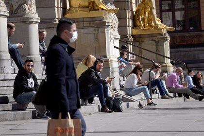 Imagen de archivo de un hombre usando una mascarilla mientras camina cerca de personas sentadas en las escaleras del teatro Kungliga Dramatiska Teatern, durante la pandemia de coronavirus, en Estocolmo, Suecia. 22 de abril, 2020. TT News Agency/Janerik Henriksson via REUTERS