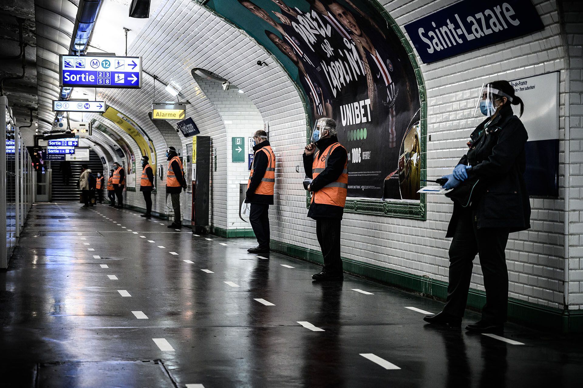 Empleados de la Autoridad Parisina del Transporte controlan que se mantenga la distancia social en la estación Saint-Lazare del metro de la capital francesa. 