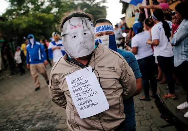 Un manifestante luce una máscara de Ortega con acusaciones de crímenes (Reuters)