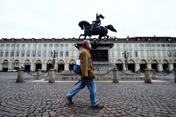 Un hombre con una máscara protectora camina en una plaza prácticamente desierta de San Carlo, en el tercer día de un encierro sin precedentes en toda Italia impuesto para frenar el brote de coronavirus, en Turín (Reuters)