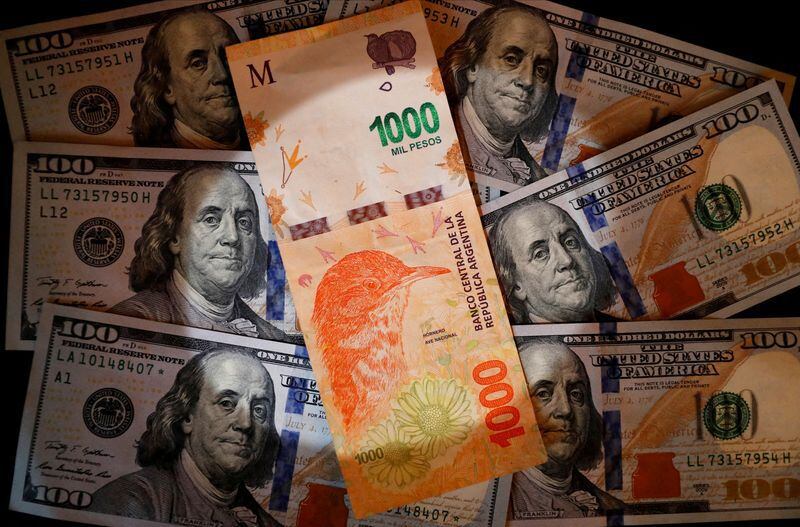 Foto de archivo. Un billete de mil pesos argentinos sobre varios billetes de cien dólares estadounidenses. Oct 17, 2022. REUTERS/Agustin Marcarian/Ilustración