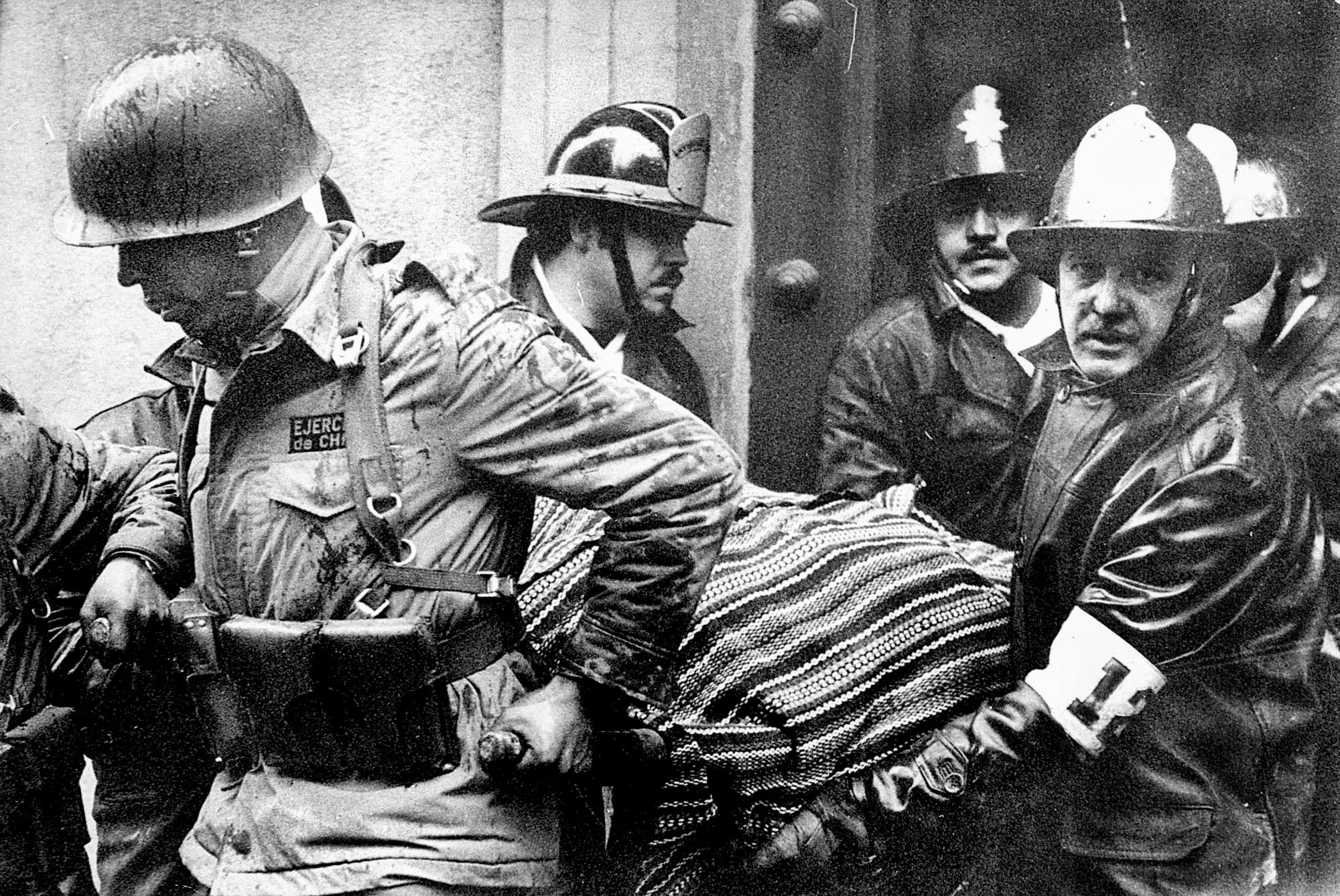 En esta imagen de archivo, soldados y bomberos sacan el cuerpo del presidente chileno Salvador Allende, envuelto en un poncho boliviano, del palacio presidencial de La Moneda (AP Foto/El Mercurio, archivo)