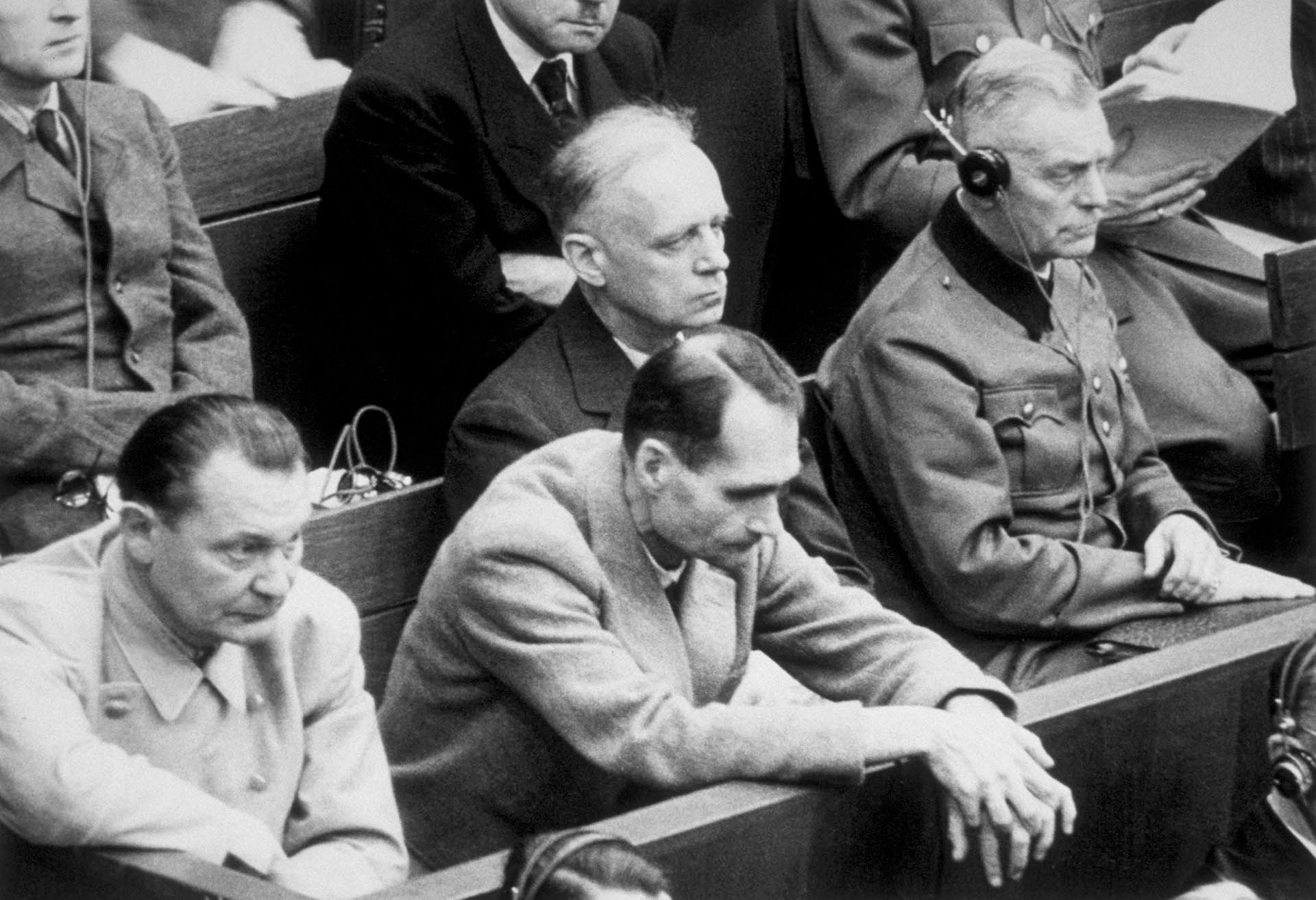 Rudolf Hess apoya sus manos sobre el banco de los acusados en Nuremberg. Junto a él: Joachim von Ribbentrop, Wilhelm Keitel, y Hermann Goering