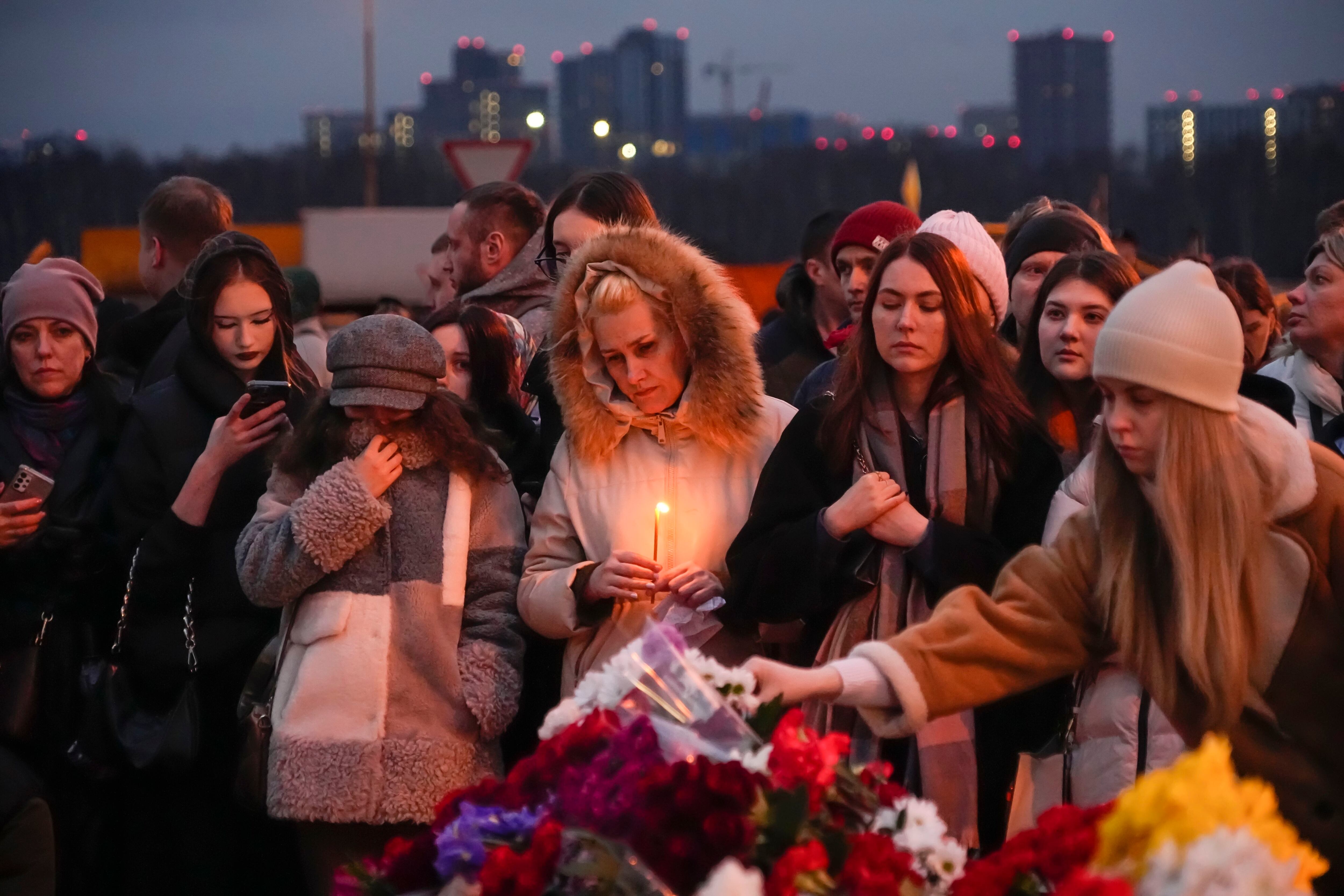 Varias personas depositan flores y encienden velas en las inmediaciones del Crocus City Hall, donde se registró un ataque que dejó más de 100 fallecidos, a las afueras de Moscú, Rusia, el 23 de marzo de 2024 (AP Foto/Alexander Zemlianichenko)