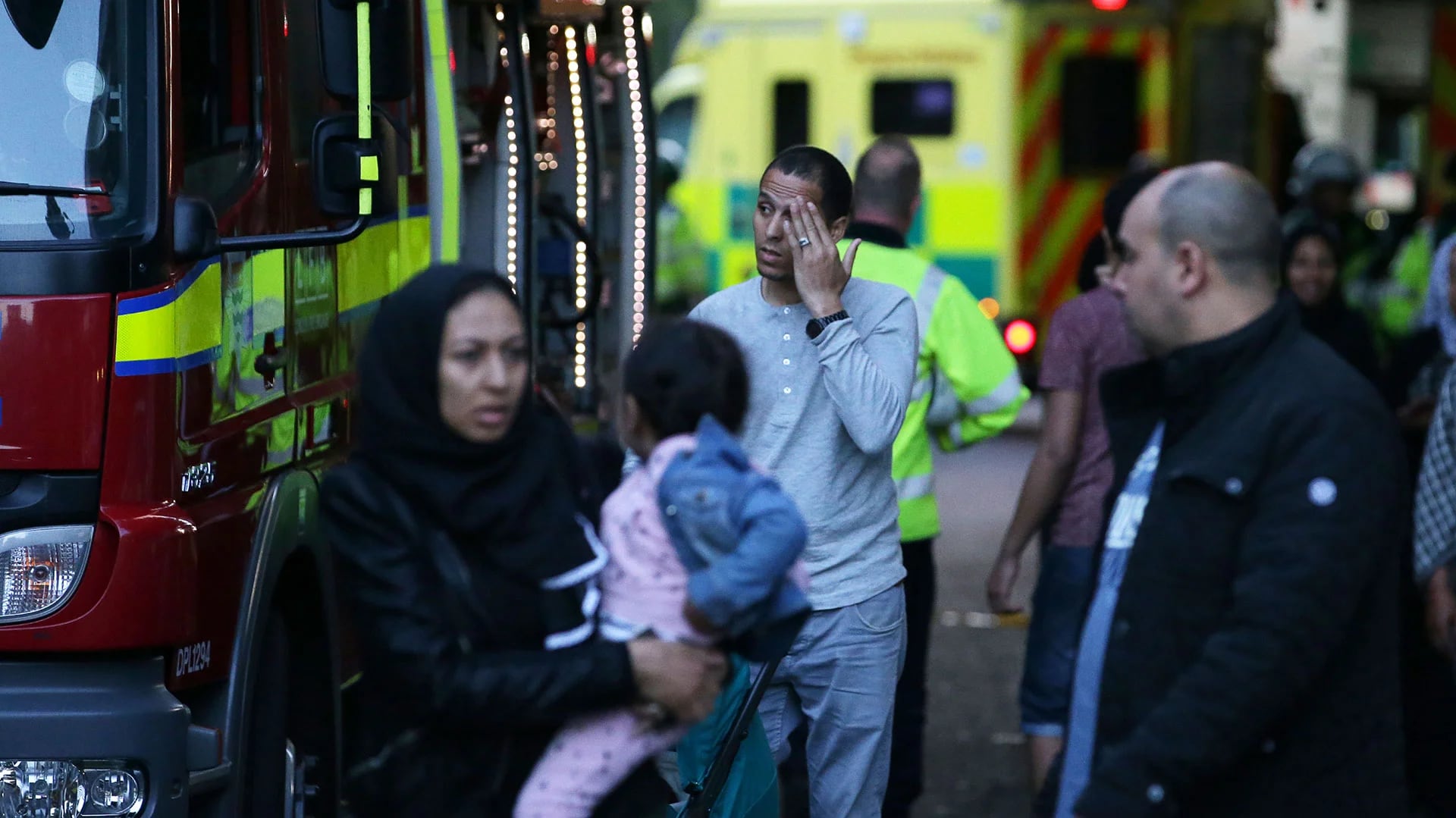 Una familia espera ser atendida junto a los rescatistas tras abandonar la torre Grenfell en Londres (AFP)