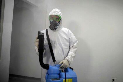 Un auxiliar del personal de aseo desinfecta un sector destinado para atender pacientes de COVID-19 en San Salvador (EFE/Miguel Lemus)