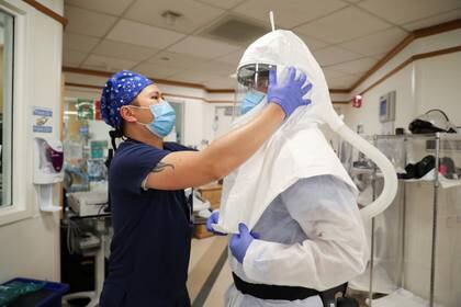 Un trabajador médico le pone un traje protector para intubar un paciente con COVID-19 ne una unidad de terapia intensiva.