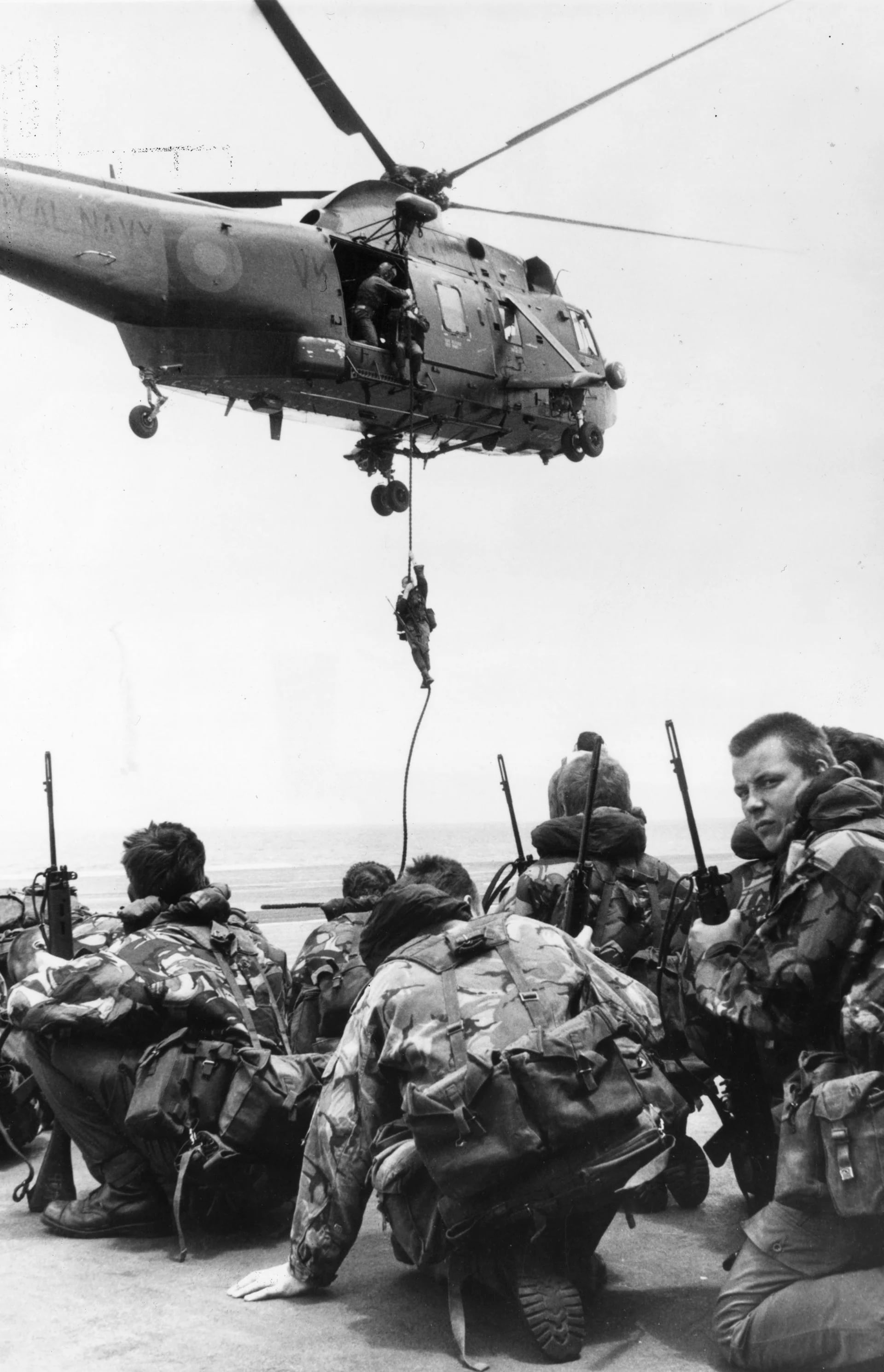 Soldados de la Marina Real esperando a ser transportados por un helicóptero Westland Sea King Waiting del las fuerzas británicas (Fox Photos/Getty Images)