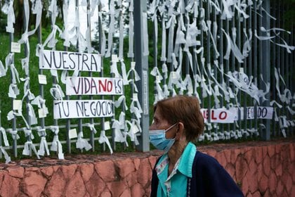Una mujer camina junto a cintas blancas, colocadas en memoria de las personas que fallecieron por el COVID-19, frente al Ministerio de Salud en Asunción el 7 de abril de 2021 (REUTERS/Mayeli Villalba)