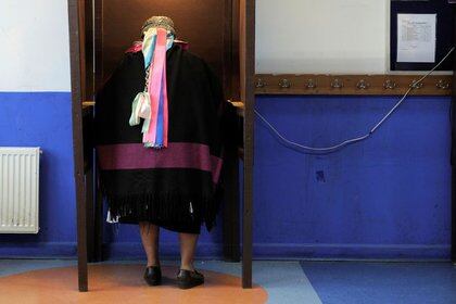 Una mujer indígena mapuche se prepara antes de emitir su voto en una escuela utilizada como centro de votación durante un referéndum sobre una nueva constitución en Cañete, Chile