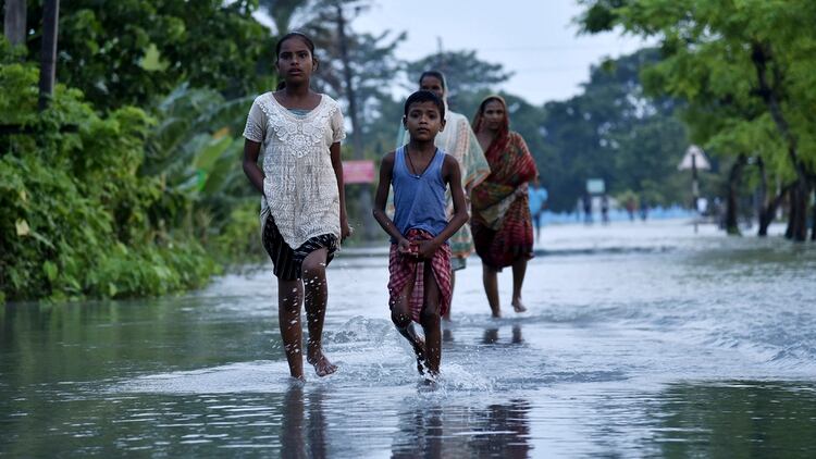 Una familia camina sobre el agua en la India (Photo by David TALUKDAR / AFP)