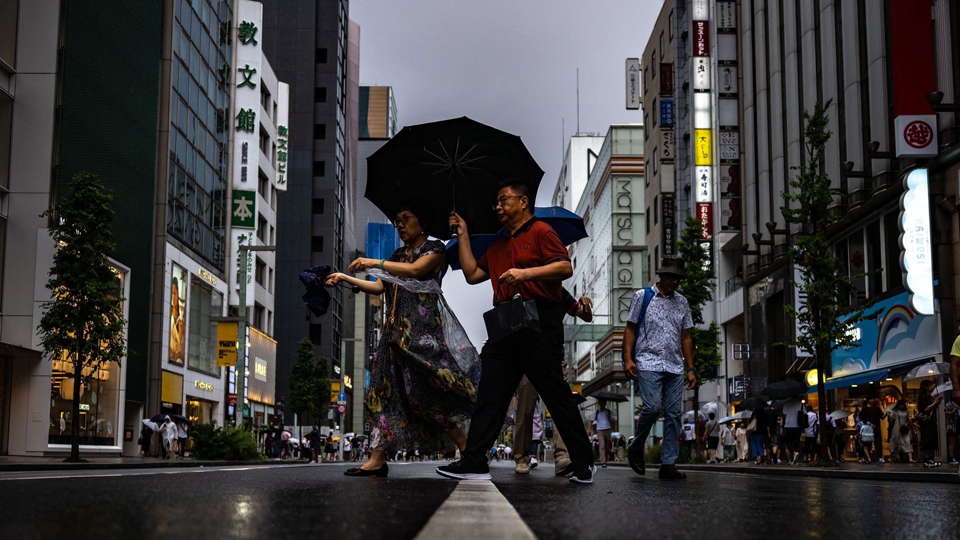 Peatones caminan con sus paraguas bajo la lluvia en el distrito de Ginza de Tokio el 13 de agosto de 2023, mientras el tifón Lan se dirige a la isla principal de Japón, Honshu. (Foto de Philip FONG / AFP)