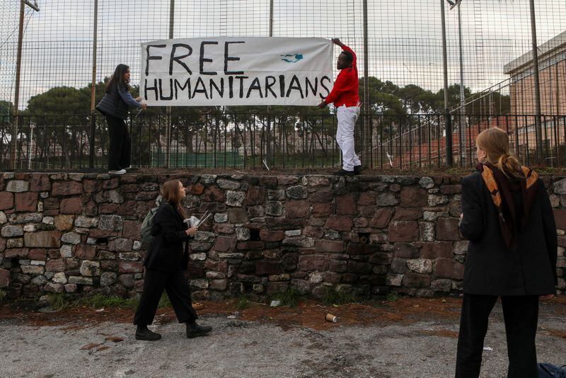 FOTO DE ARCHIVO: Dos personas cuelgan una pancarta en apoyo a un grupo de cooperantes, contra los que se han presentado cargos por proveer ayuda humanitaria, en el exterior de un tribunal en Lesbos, Grecia, el 13 de enero de 2023. REUTERS/Elias Marcou
