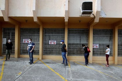 Personas mantienen distancia social mientras esperan para hacerse una prueba de detección del coronavirus afuera de un laboratorio en Tegucigalpa, Honduras (REUTERS/Jorge Cabrera)