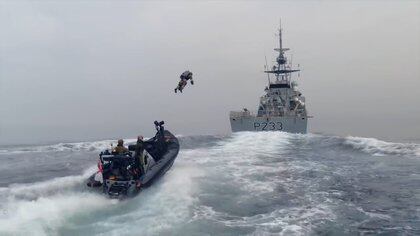 Un marine usando un jetpack vuela desde un bote hasta un barco en medio de una operación de prueba militar. (captura de video)
