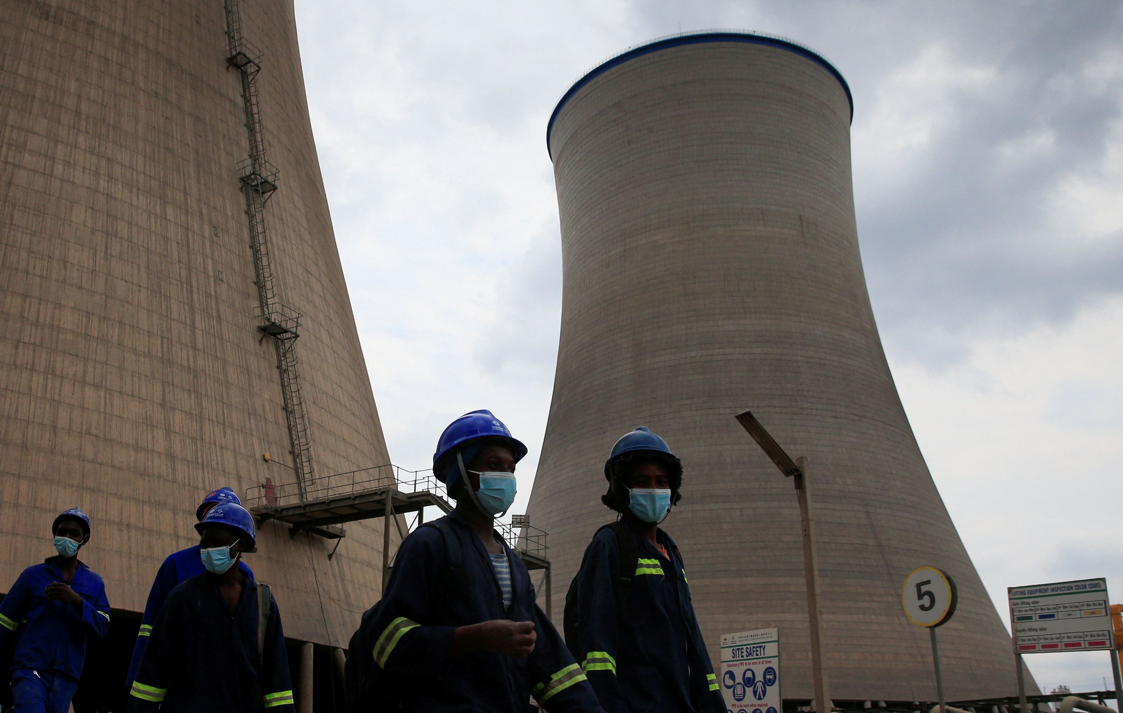 Trabajadores caminan bajo las torres de refrigeración de la Fase 8 de la central eléctrica de Hwange de Zimbabue, construida por empresas chinas (REUTERS/Philimon Bulawayo)
