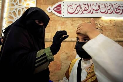 Una mujer ajusta la gorra de su hijo con una máscara facial, durante el mes de ayuno del Ramadán, en medio de la preocupación por la propagación de la enfermedad coronavirus (COVID-19), en la ciudad vieja de Sidón, en el sur del Líbano, el 19 de mayo de 2020. Foto tomada el 19 de mayo de 2020. REUTERS/Ali Hashisho