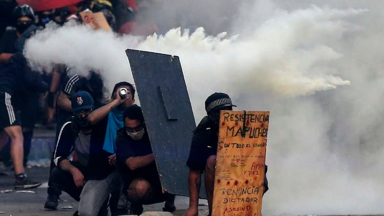 Manifestantes durante una represión a las protestas en Chile (Photo by JAVIER TORRES / AFP)